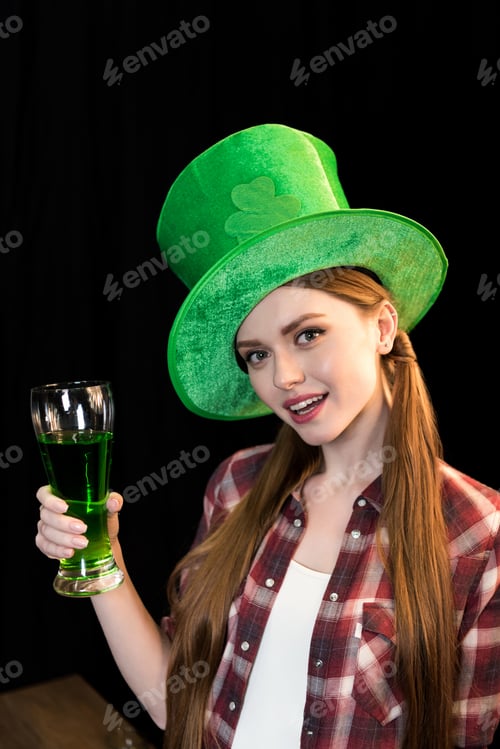Preview: smiling woman holding glass of beer in hand on St.Patrick's day on black