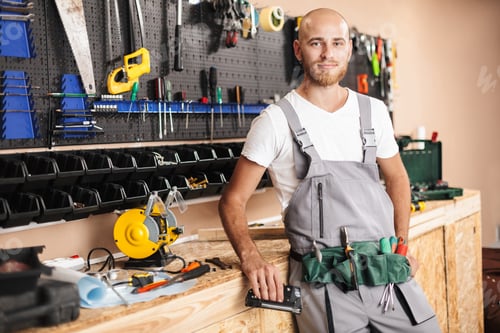 Preview: Smiling foreman in work clothes holding stapler in hand dreamily
