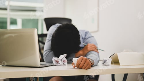 Preview: Overworked young man office worker fall asleep on his office desk.