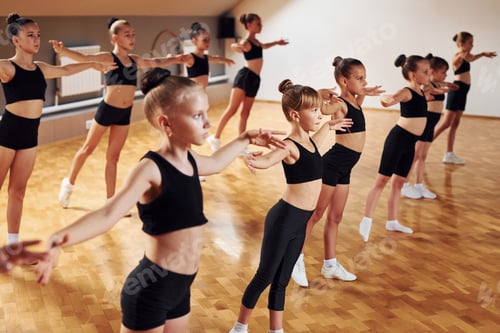 Preview: Standing in the row. Group of female kids practicing athletic exercises together indoors