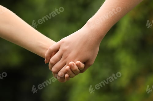 Preview: Woman and child holding hands outdoors, closeup