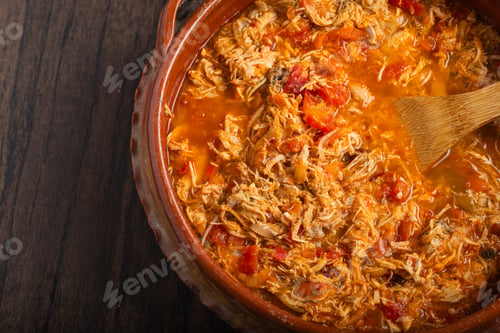 Preview: Authentic mexican chicken tinga, typical mexican food prepared in a clay pot on a wooden table.