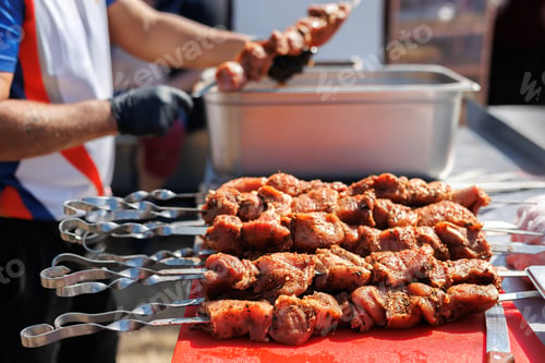 Preview: A man strands pickled meat on a skewer. Street food at the fair.