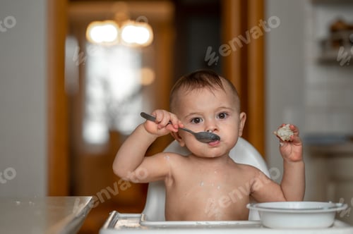 Preview: A baby stained in porridge eats on his own