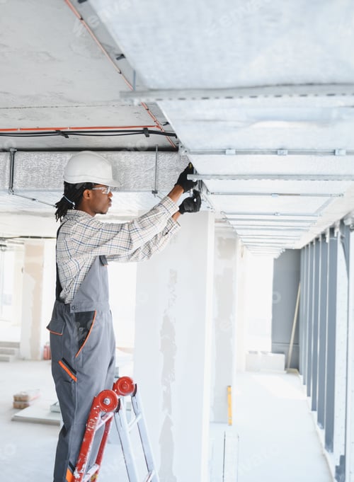 Construction worker installing ventilation system on a ladder in building site