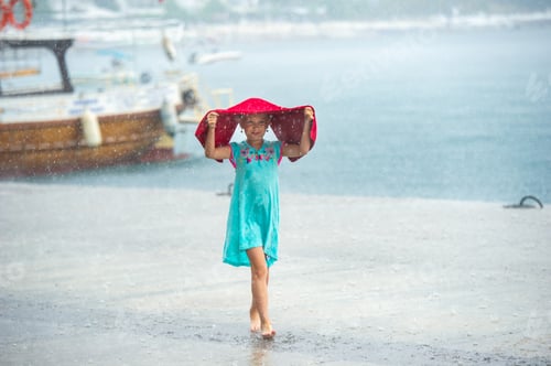 Preview: A little girl in a turquoise dress walks in the rain on the embankment in Turkey