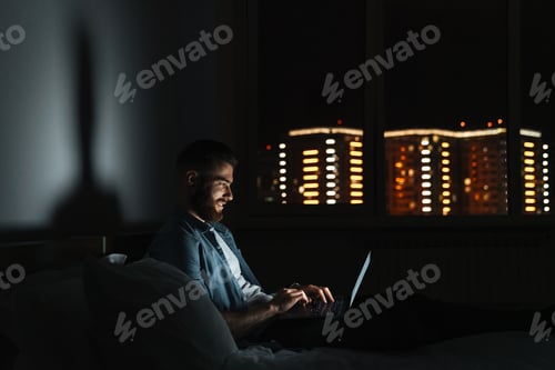 Preview: young bearded man laying on bed at home at night