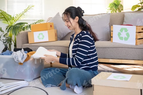 Preview: A young woman separates unused clothes and prepares them for donation or recycling in order to