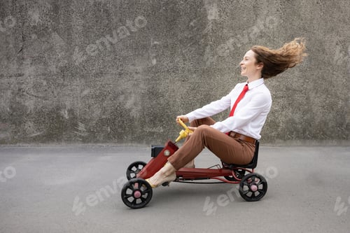 Preview: Funny businesswoman driving retro pedal car outdoor