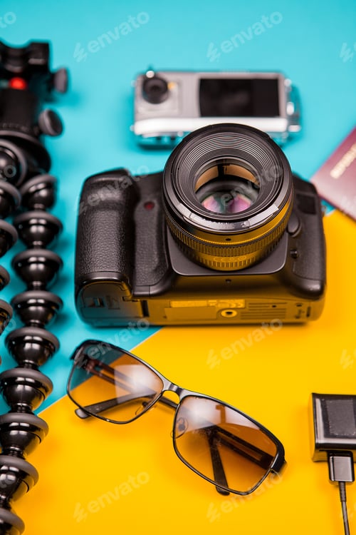 Preview: DSLR and action camera next to a tripod, sunglasses and passport