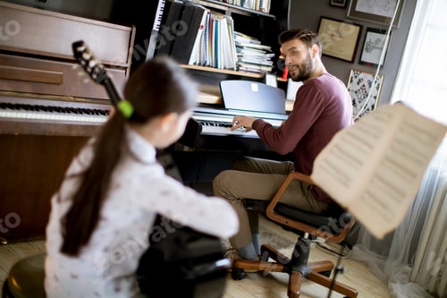 Preview: Little girl playing guitar with her music teacher in the rustic apartment