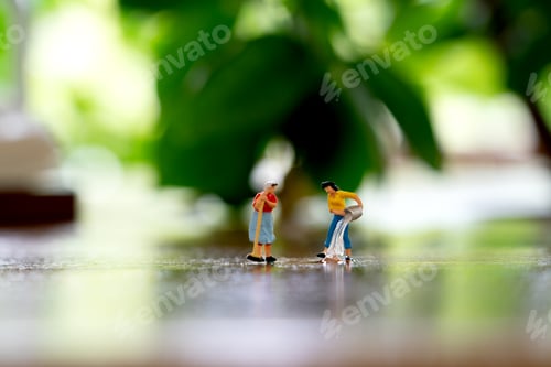Preview: Miniature figurines performing cleaning tasks on a shiny surface