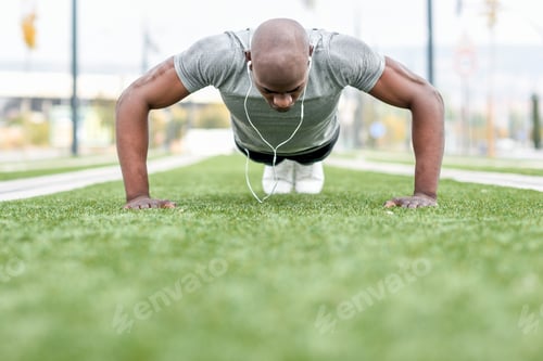 Preview: Fitness black man exercising push ups in urban background