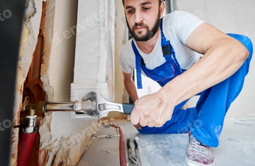 Preview: Plumber screwing plumbing fittings with a wrench