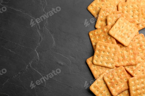 Preview: Many delicious crackers on black table, flat lay. Space for text