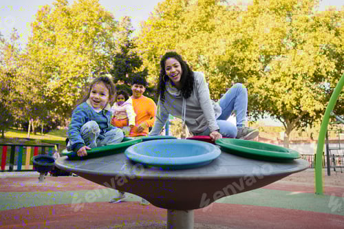Preview: Happy latin parents playing with their children on a fun roundabout. Latin family