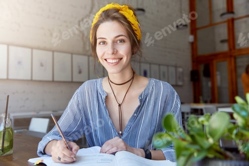 Preview: Indoor shot of busy student female with dark eyes, oval face and cheerful expression studying new to