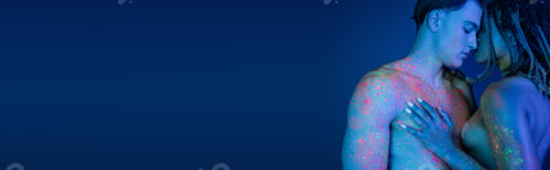 Preview: intimate moment of interracial couple in colorful neon body paint on blue background with cyan