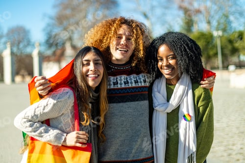 Preview: Happy multi ethnic friends showing rainbow flag at gay pride parade