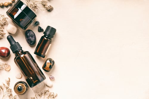 Preview: Essential Oil Bottles with Crystals and Dried Herbs on Beige Surface