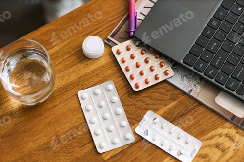 Preview: Assorted Pills and Blister Packs Arranged near Laptop Representing Healthcare