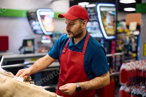 Preview: Male vendor working at organic food section in a supermarket.