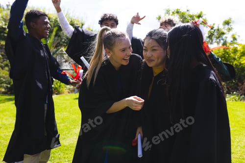 Preview: Graduating students celebrating outdoors, smiling and holding diplomas in excitement