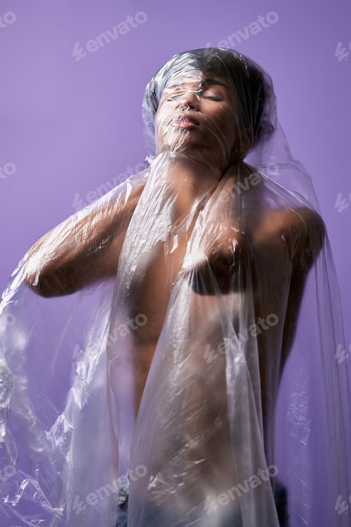 Preview: Portrait of young man standing in plastic bag on muscular nude body. Claustrophobia problem