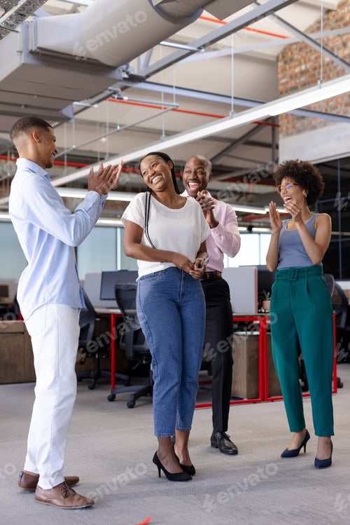 Preview: Colleagues celebrating success in modern office, smiling and applauding together