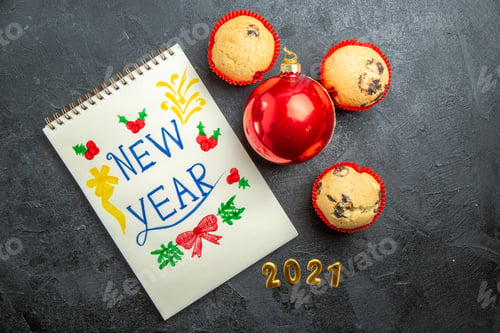 Preview: Top view of greeting golden text notebook and new year decorations on dark background