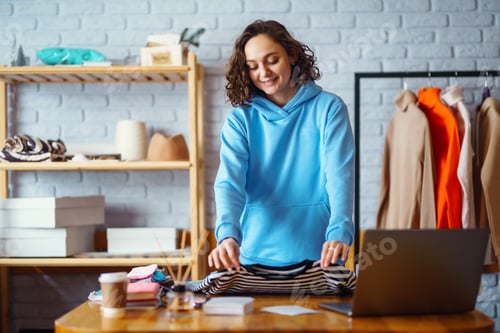 Preview: Smiling woman takes notes of orders from with laptop. Dropshipping owner works.