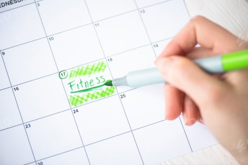 Preview: Cropped view of woman pointing with marker pen on fitness lettering in to-do calendar on wooden