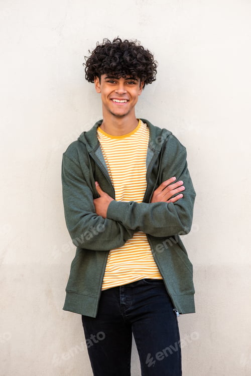 Preview: smiling young man with arms crossed by white wall