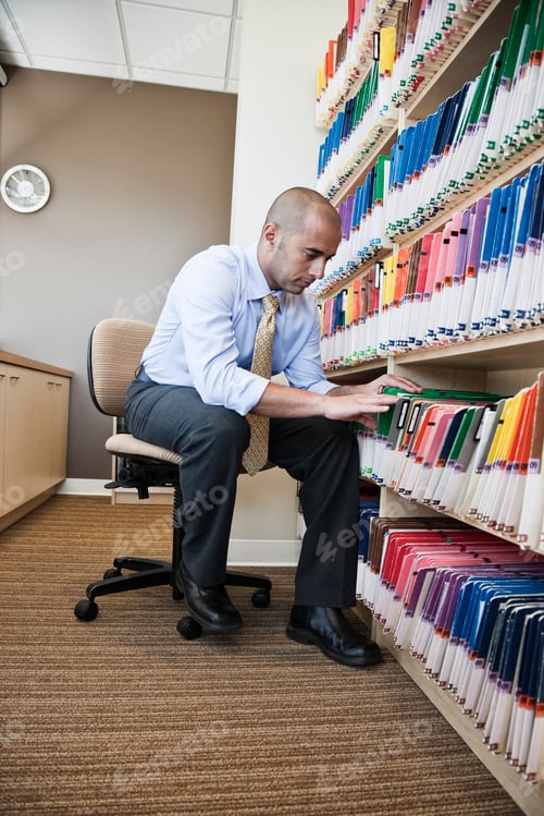 Preview: A Middle Eastern businessman looking through file folders, searching through paperwork for