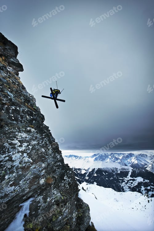 Aperçu: Skier performing a midair twist against a stunning mountain backdrop