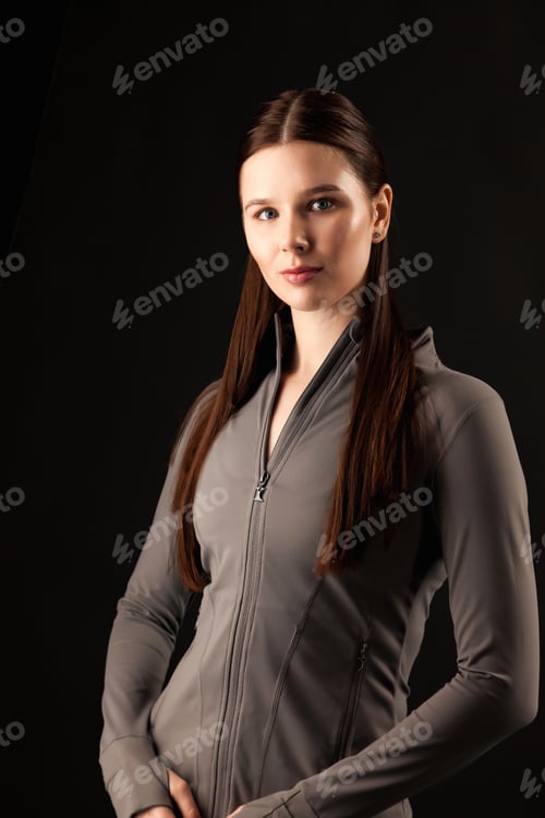 Preview: Woman in Gray Sportswear Posing in Studio Looking Directly at the Camera