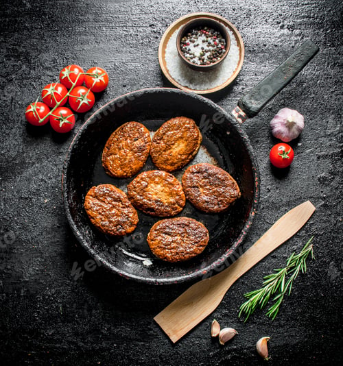 Preview: Cutlets in the pan with a wooden spatula and cherry.