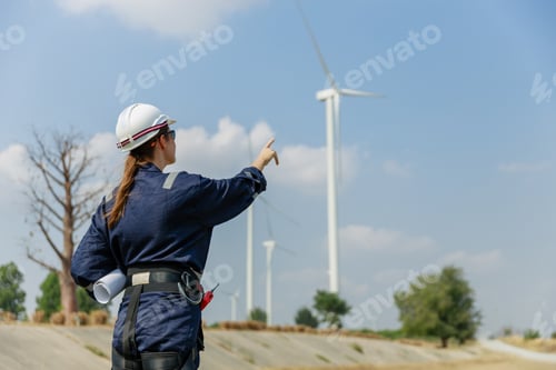 Preview: woman engineer worker wearing safety uniform holding and reading blueprint working about renewable