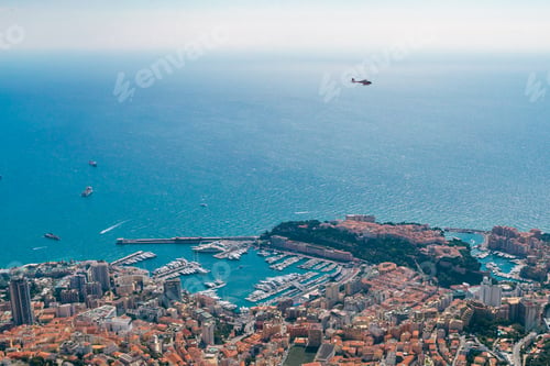 Preview: Aerial shot of a cityscape on the seashore in Monaco and a helicopter flying over the sea