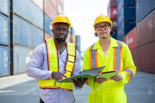 Preview: Asian and black engineers check cargo at shipping container