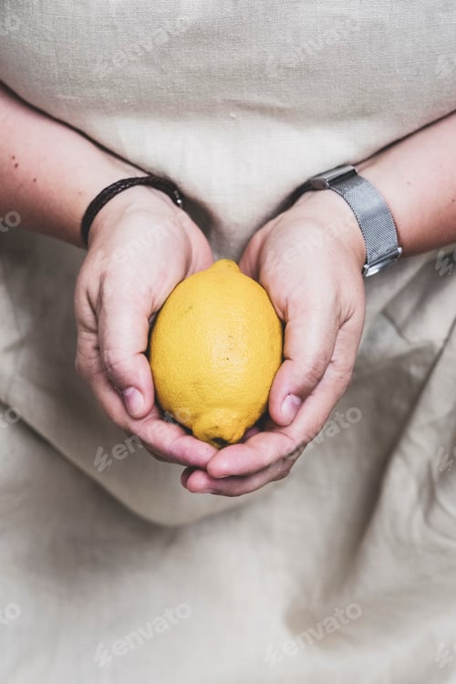 Preview: Close up of person holding fresh lemon.
