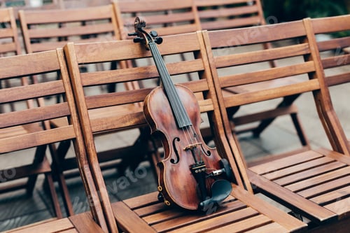 Preview: Violin on wooden chair in garden. Preparation for concert or performance.