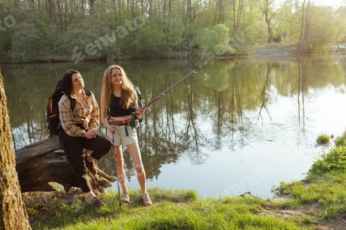 Preview: Smiling hikers by the lake with trekking poles, enjoying springtime adventure in the forest.