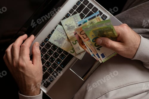 Preview: person with money in their hands and laptop