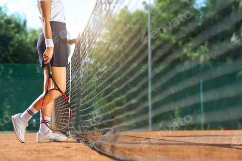 Preview: Athletic woman standing near net on court with racket in hands