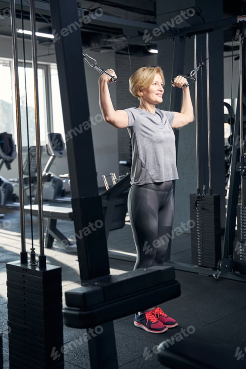 Preview: Sporty woman using gym trainer in fitness center