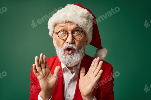 Preview: astonished Santa in christmassy hat and glasses gesturing with slightly open mouth, winter concept