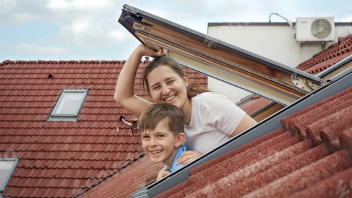 Preview: Happy smiling mother with son opens attic windows and looks outdoor. Concept of family happiness