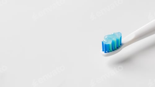Preview: A white toothbrush with blue bristles with gel toothpaste in close-up. Oral hygiene. Copy space