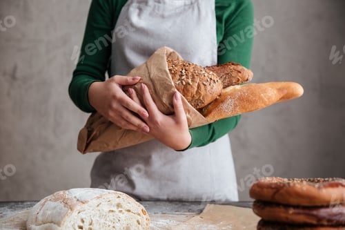 Preview: Cropped image of female baker holding bag with bread